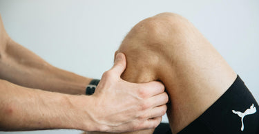 Knie van een persoon waarbij de fysio bezig is met een revalidatie oefening